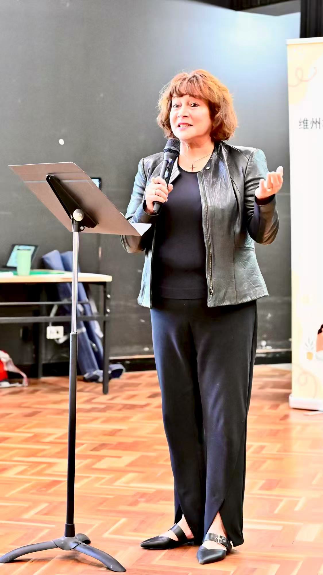 A speaker in a black jacket speaking at the lectern