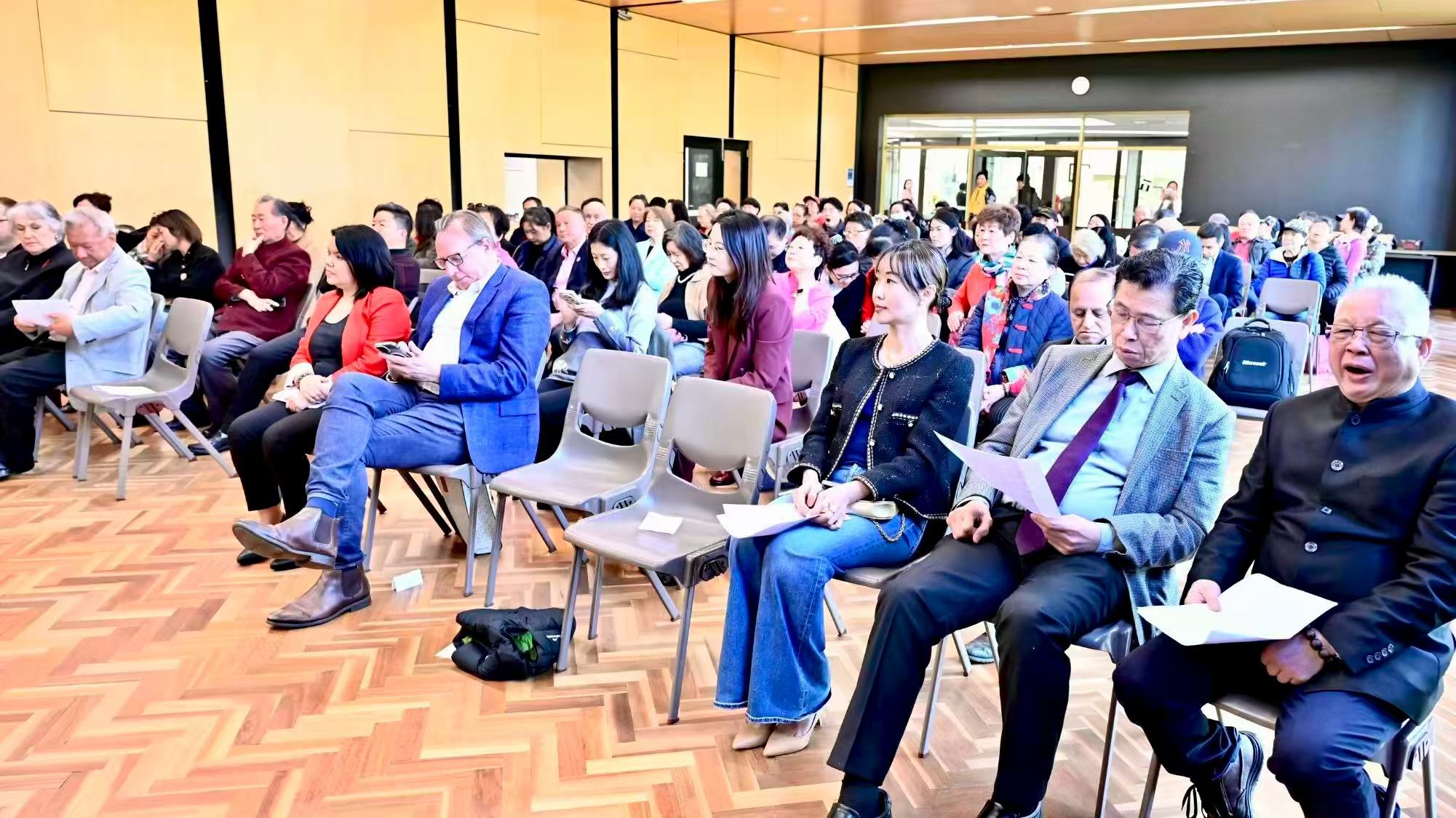 Guests seated in the audience, some holding event programmes