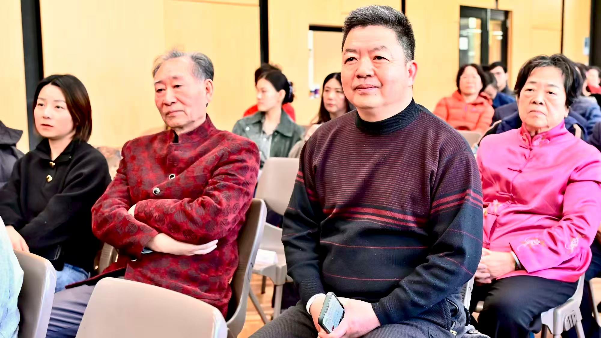 Guests wearing red, dark and pink clothing listening in the audience